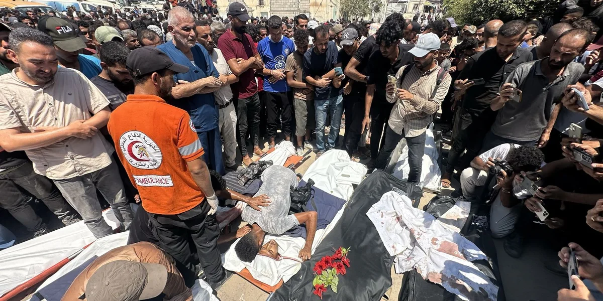 Mënsche biede virun de Läiche vu Palestinenser, déi bei der israeelescher Attack op d’Nasser Spidol zu Khan Younis ëmkoum sinn. | © EPA/HAITHAM IMAD